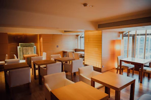 A cozy Scandinavian-style restaurant interior bathed in warm light, with rustic wooden tables set for a meal.
