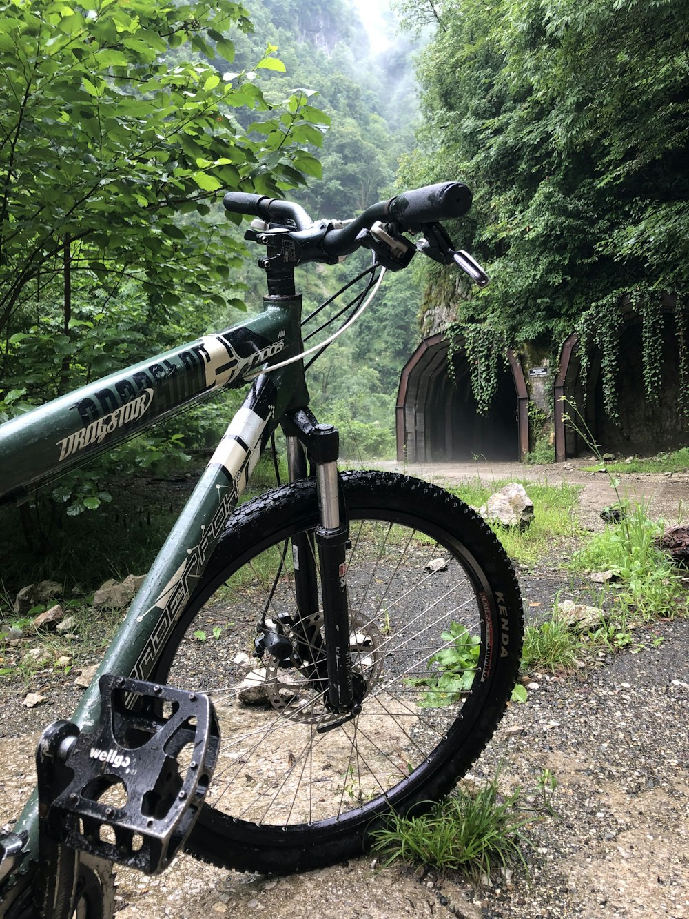 a mountain bike parked on the side of a dirt road