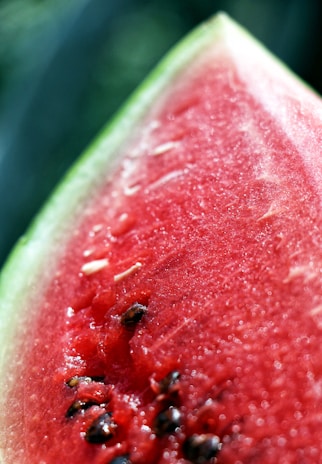 A vibrant, juicy watermelon sliced open, resting on a rustic wooden table with sunlight streaming in.