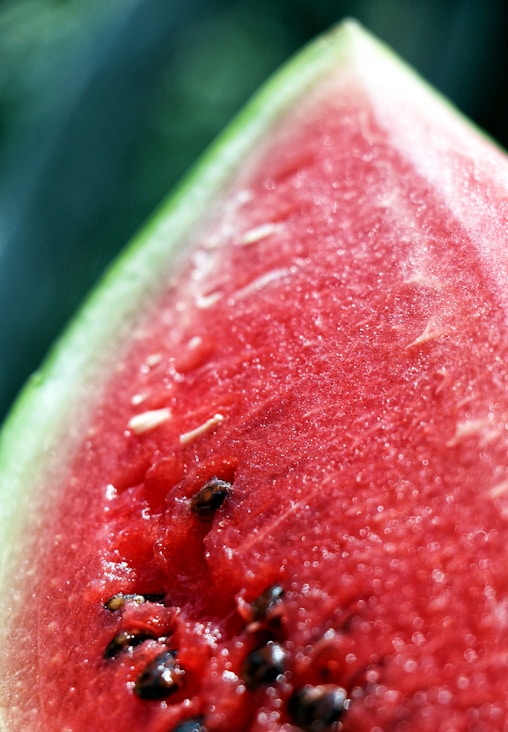 A vibrant, juicy watermelon sliced open, resting on a rustic wooden table with sunlight streaming in.