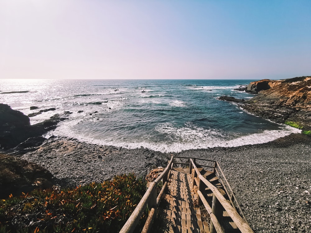 brown wooden stairs on rocky shore during day