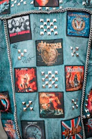 A collection of punk rock patches and pins arranged on a denim vest.