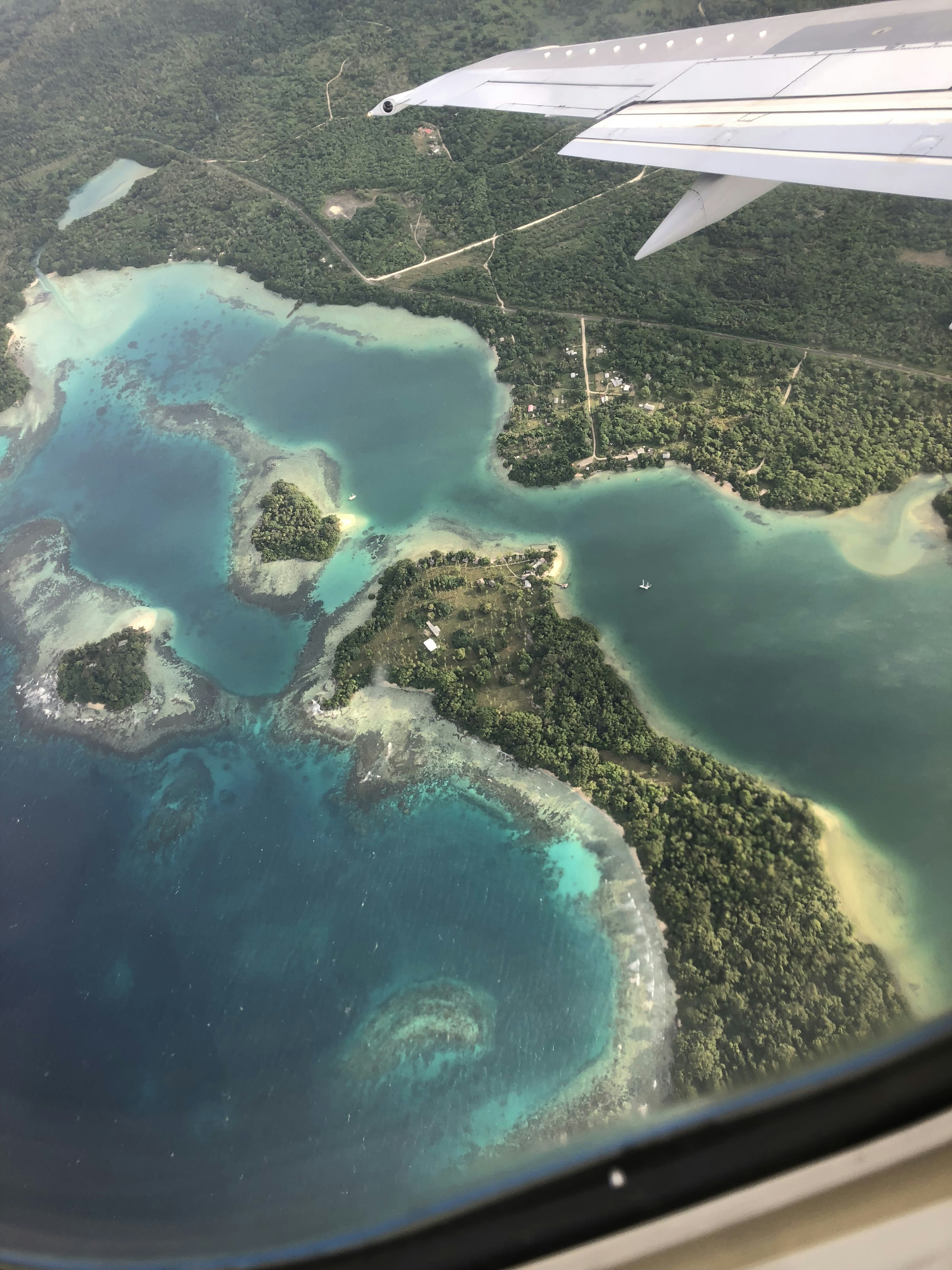 Airplane flying over tropical Philippine islands with turquoise ocean and lush green landscape below