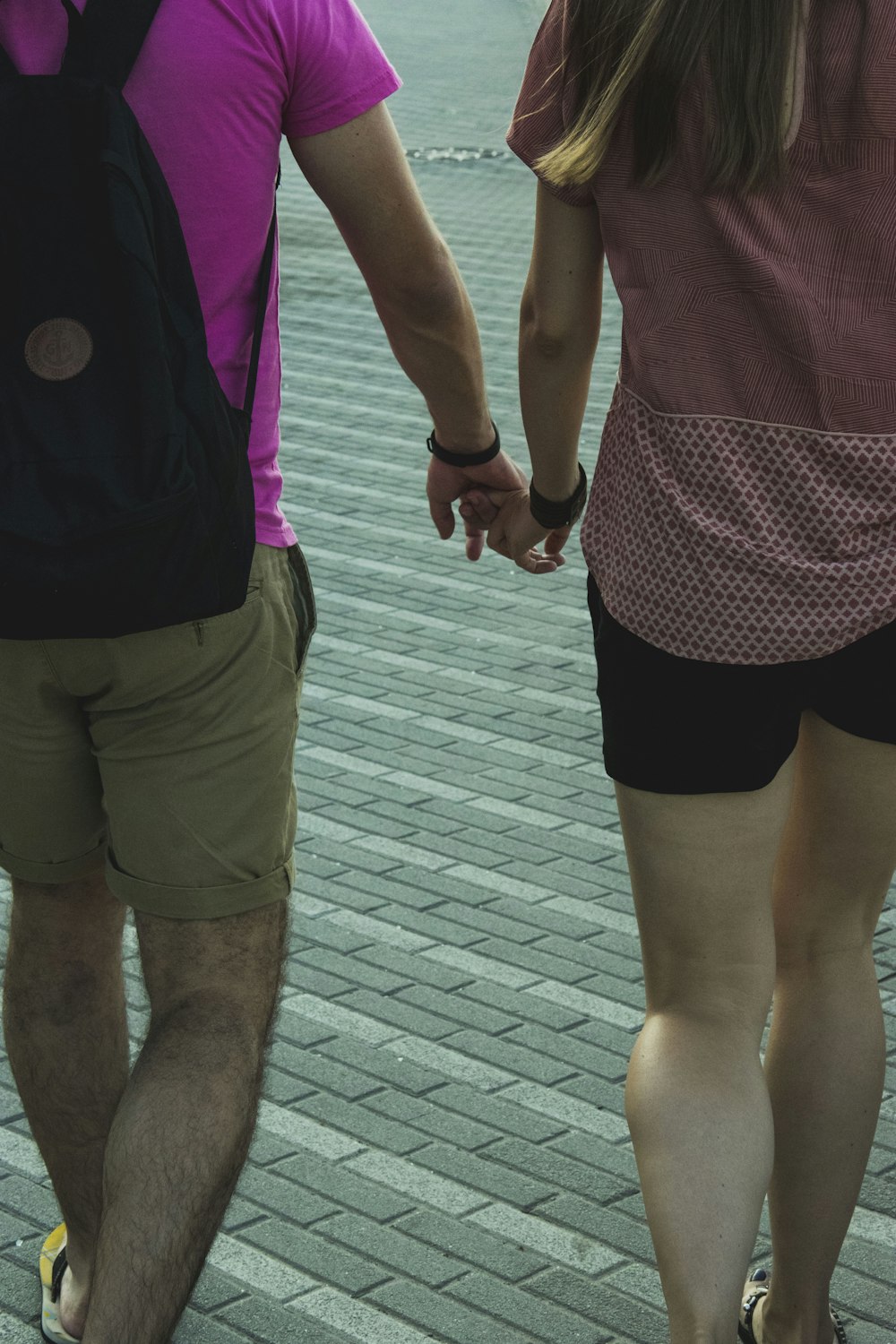 man and woman holding hands while walking