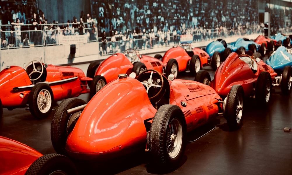 a row of red race cars sitting on top of a black floor