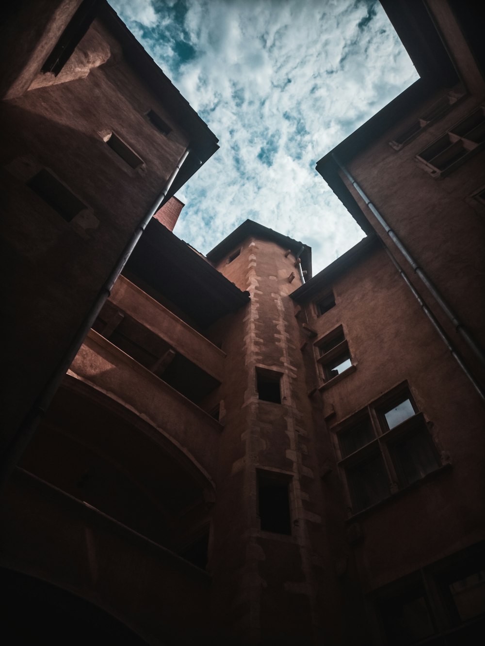 흐린 하늘 아래 갈색 콘크리트 건물의 로우 앵글 사진