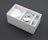 A neatly arranged white box containing a power adapter, a coiled charging cable, and an audio cable. The box is sectioned into compartments, neatly organizing the electronic accessories.