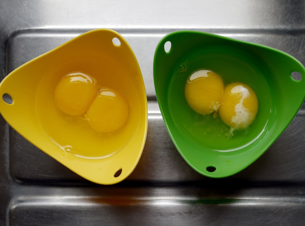 two egg yolk in each green and yellow bowls