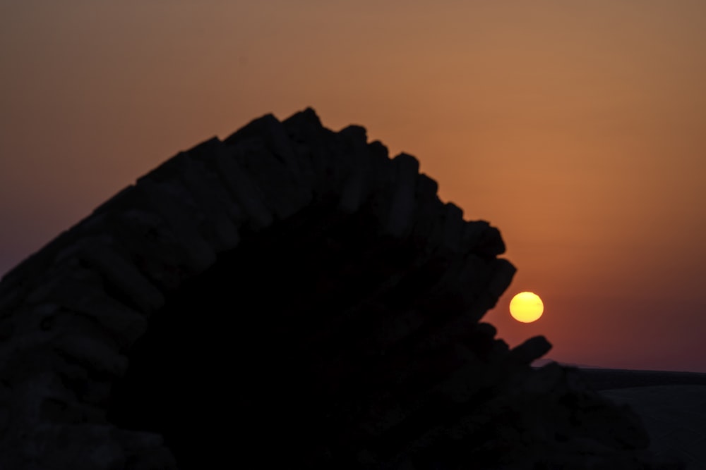 the sun is setting behind a rock formation