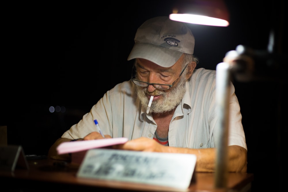 man in white button-up t-shirt writing on paper