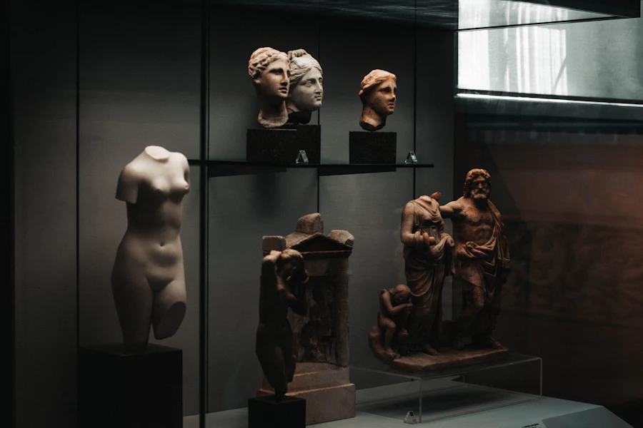 Marble figures and heads lit against a dark museum wall.