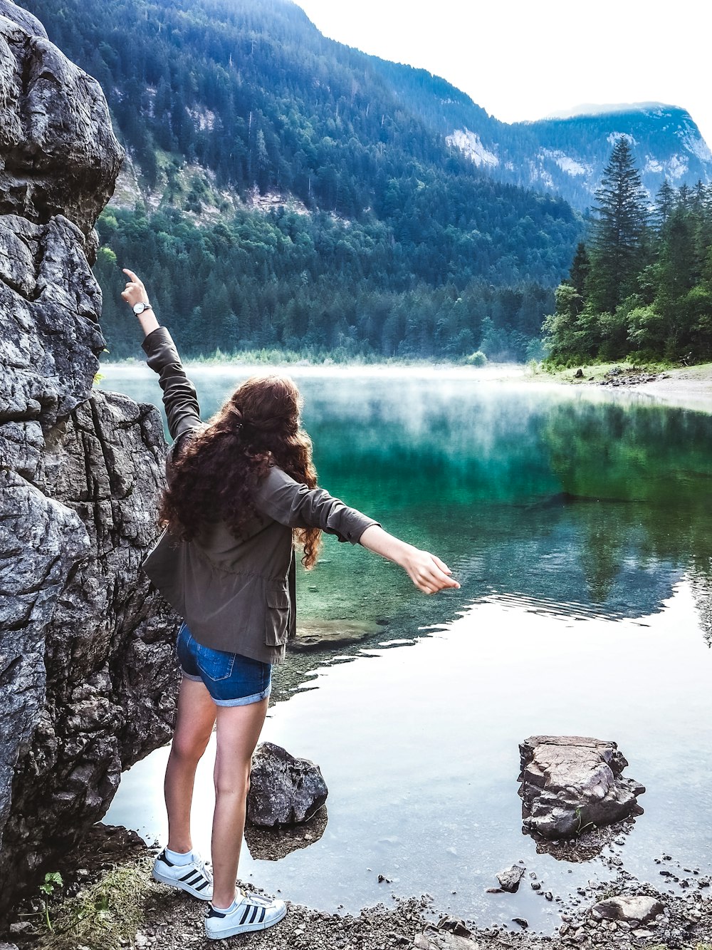 women standing near rock formation and body of water during daytime