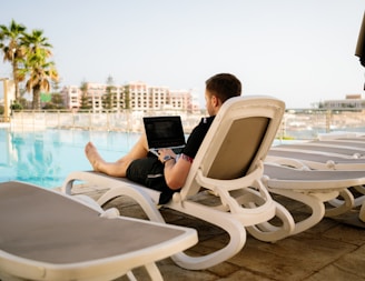 man on sun lounger using laptop travel nomad