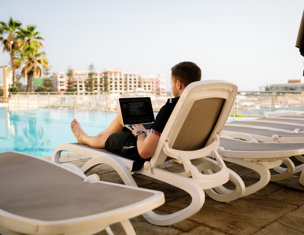man on sun lounger using laptop