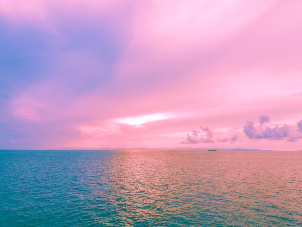 body of water under pink sky
