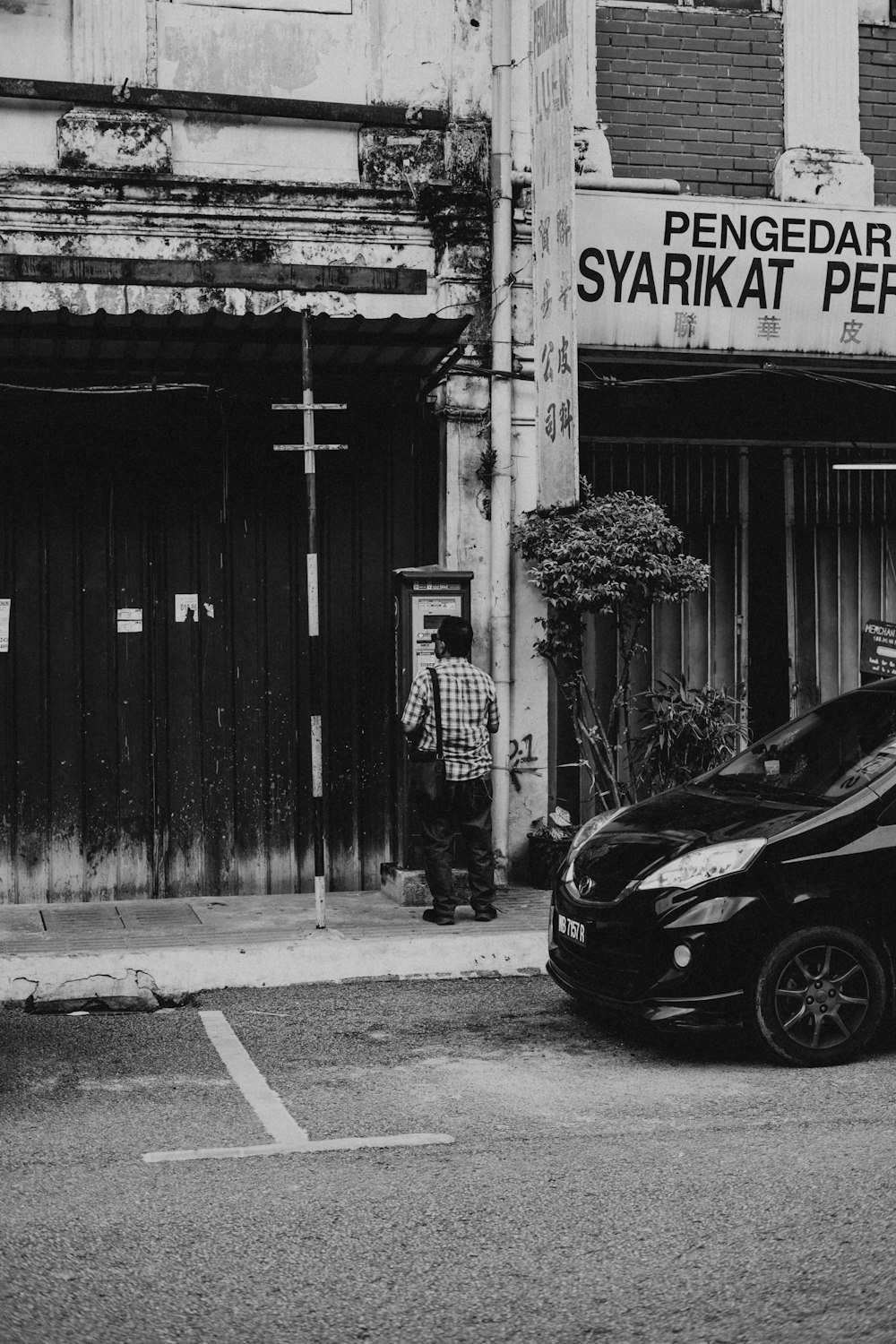 a black and white photo of a car parked in front of a building