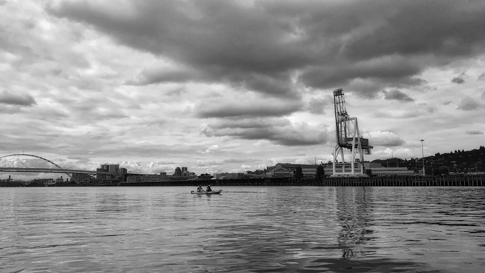 grayscale photo of person riding boat on body of water