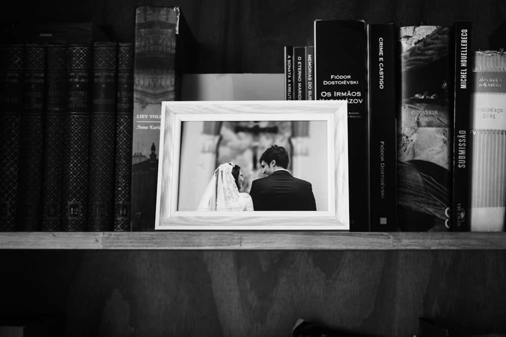 grayscale photo of photo frame on wooden shelf