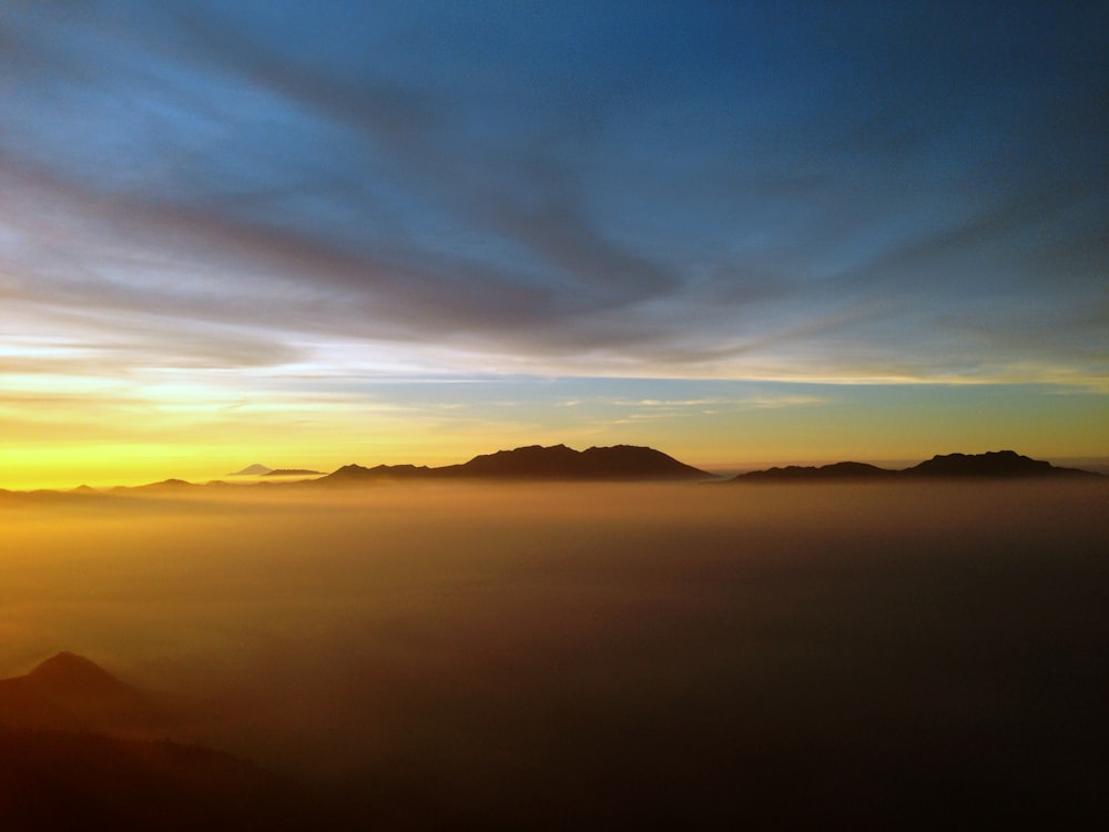 the sun is setting over a mountain range