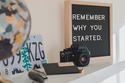 shallow focus photo of black SLR camera on white wooden shelf