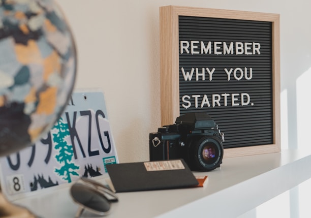 shallow focus photo of black SLR camera on white wooden shelf