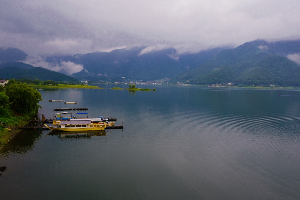 a yellow boat floating on top of a lake surrounded by mountains