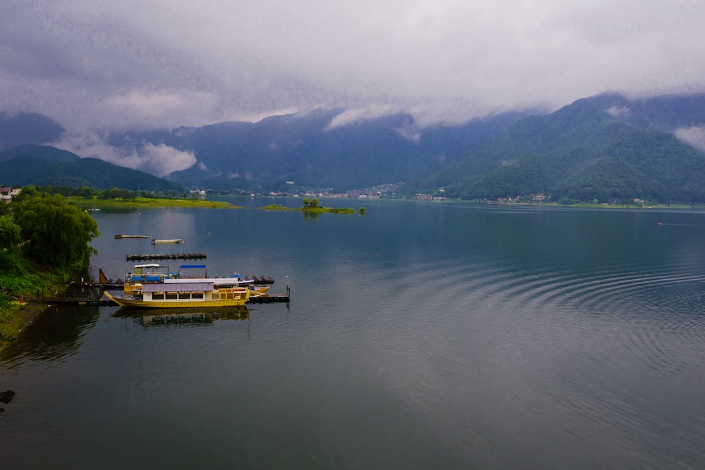 Un bateau jaune flottant au sommet d’un lac entouré de montagnes