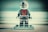 A Lego figurine wearing a detailed red and black suit with a helmet stands on a small platform. The background is blurred, giving the image a soft focus.