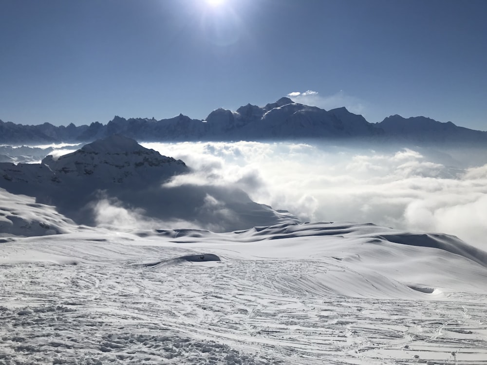 the sun is shining over a snowy mountain range