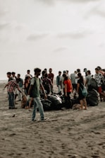 A diverse group of volunteers happily collecting litter on a sunny Mauritian beach.