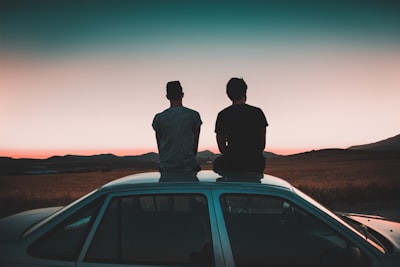 two men sitting on vehicle chill teams background