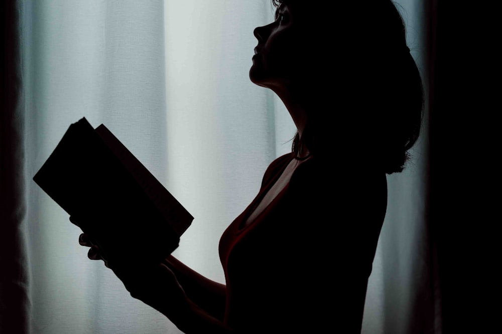 silhouette of woman holding book