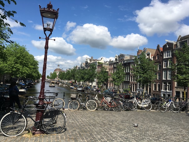 A vibrant street scene in Amsterdam with bicycles and historic buildings under a clear blue sky.
