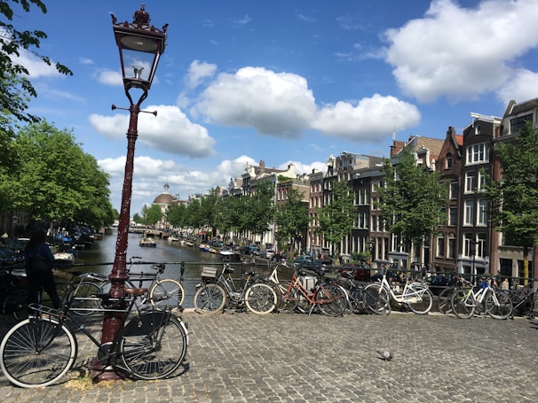 A vibrant street scene in Amsterdam with bicycles and canals under a bright sky.