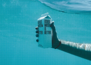 person holding boxed water underwater