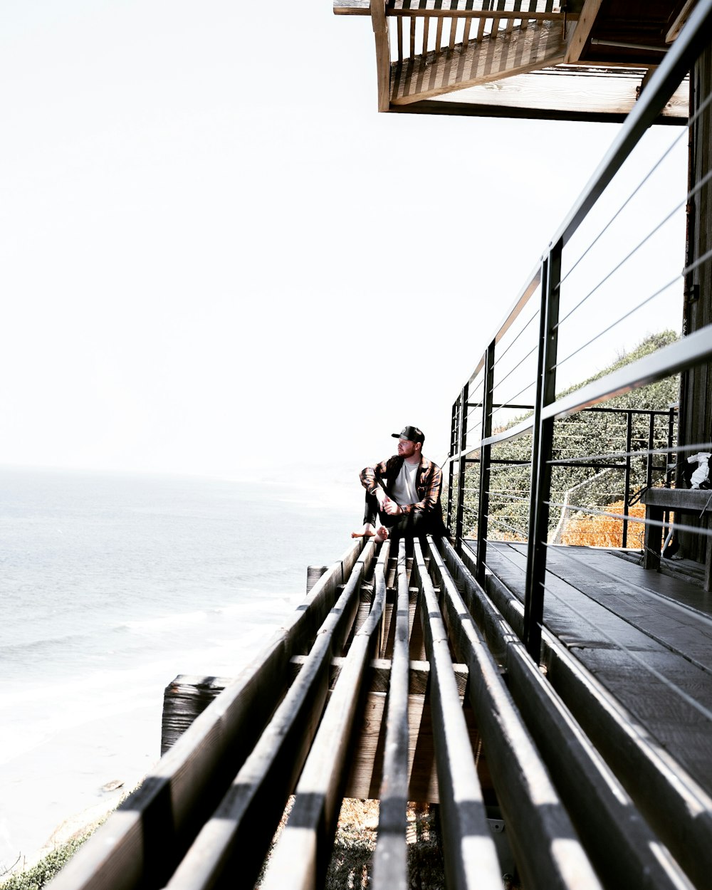 man sitting on grey surface near ocean