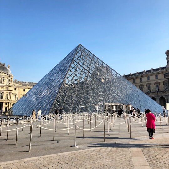 woman standing in front of stanchion in Louvre France