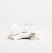 A white, sleek container with the brand name 'Candid', a small bottle labeled 'Whitener', and a clear dental aligner rest on marble slabs. The composition is minimalist with an emphasis on dental care products.