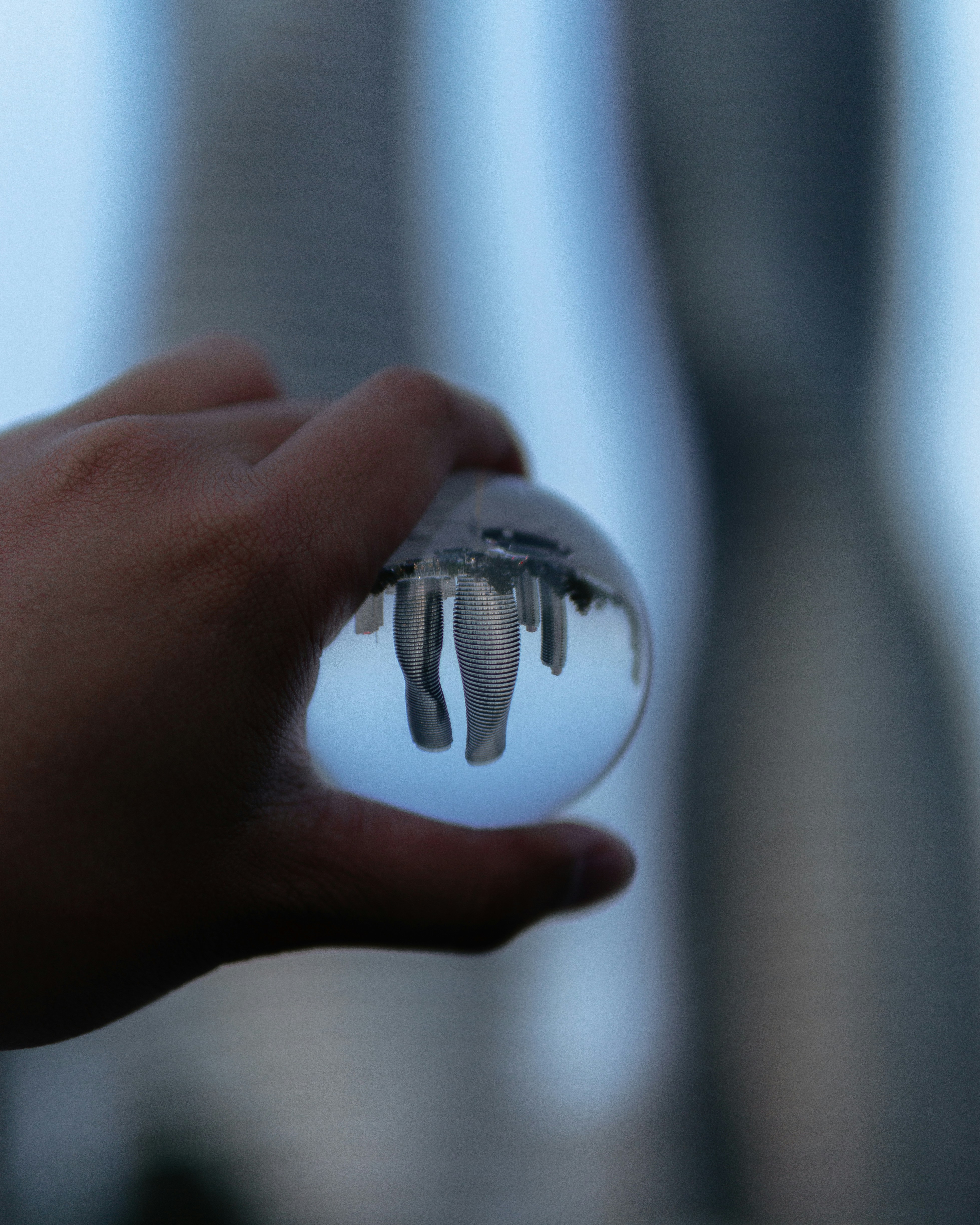 person holding clear glass ball with reflection of city