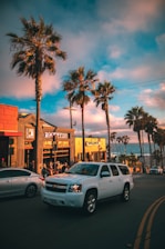 white Chevrolet Tahoe running near parked vehicles