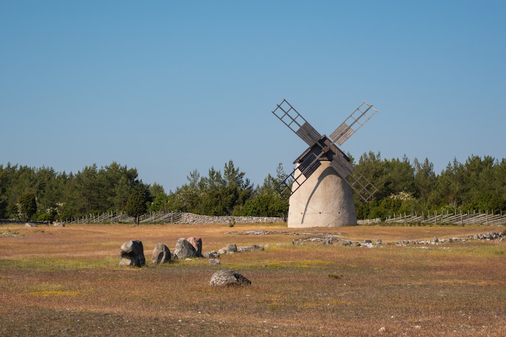 Un mulino a vento in un campo con alberi sullo sfondo