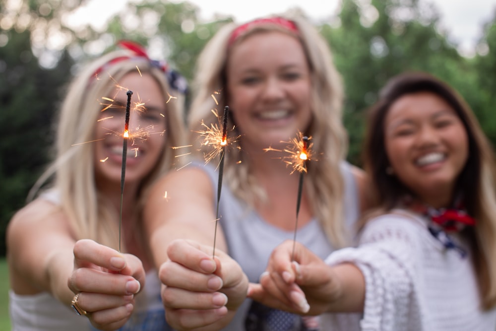 three smiling women holding sparklers