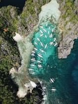 aerial photography of boats beside mountain during daytime