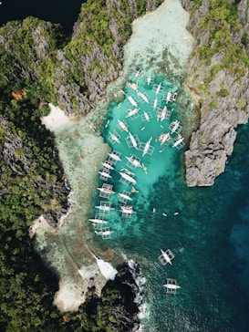 aerial photography of boats beside mountain during daytime