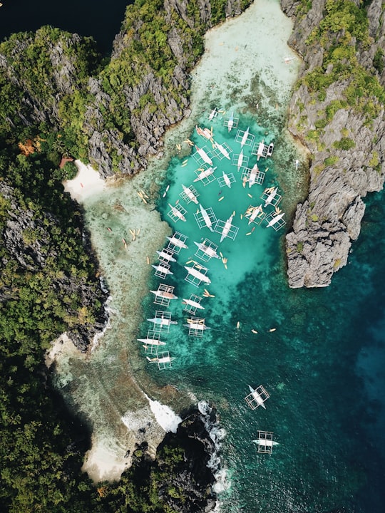 aerial photography of boats beside mountain during daytime in El Nido Philippines