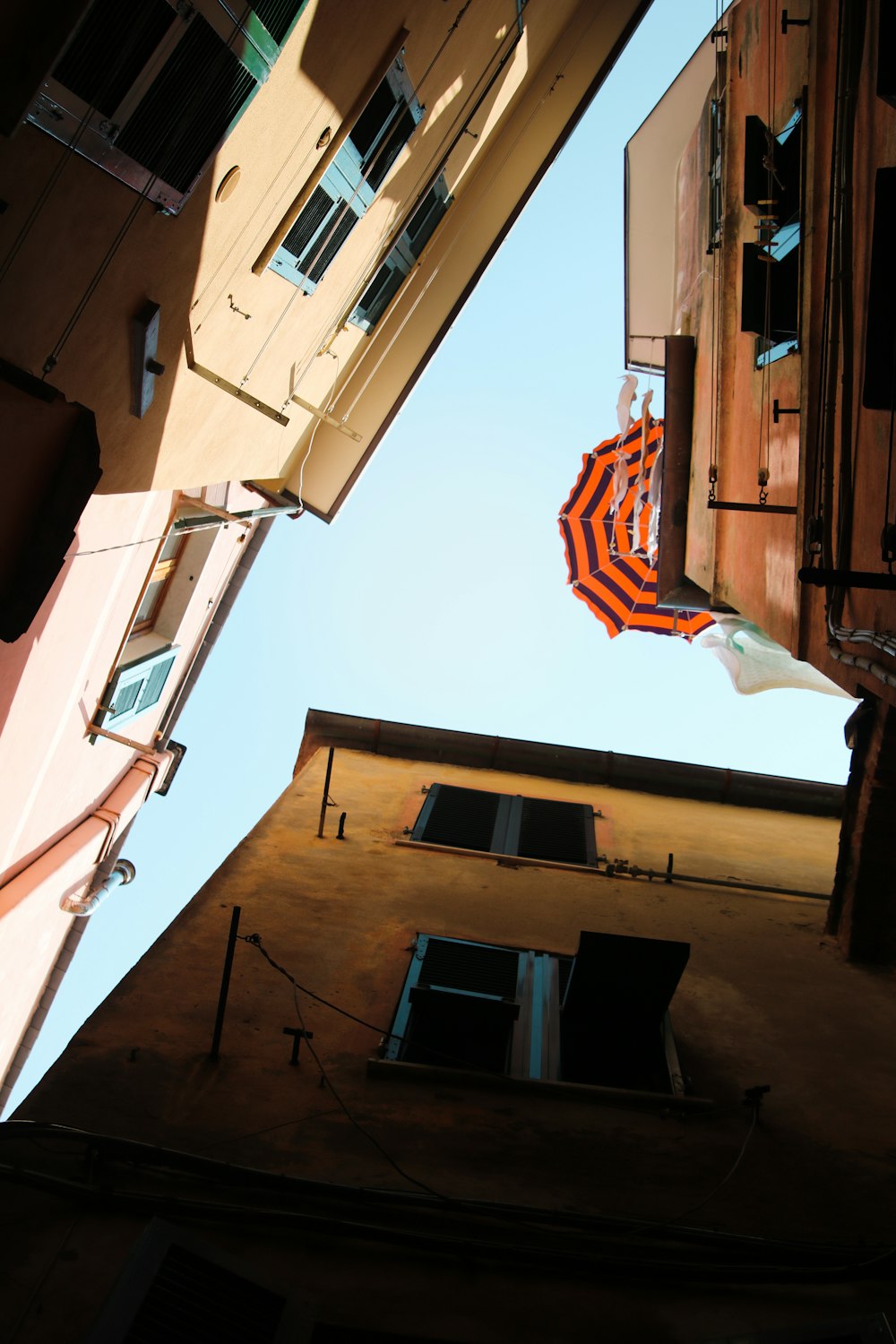 ein orange-weißer Regenschirm, der an der Seite eines Gebäudes hängt