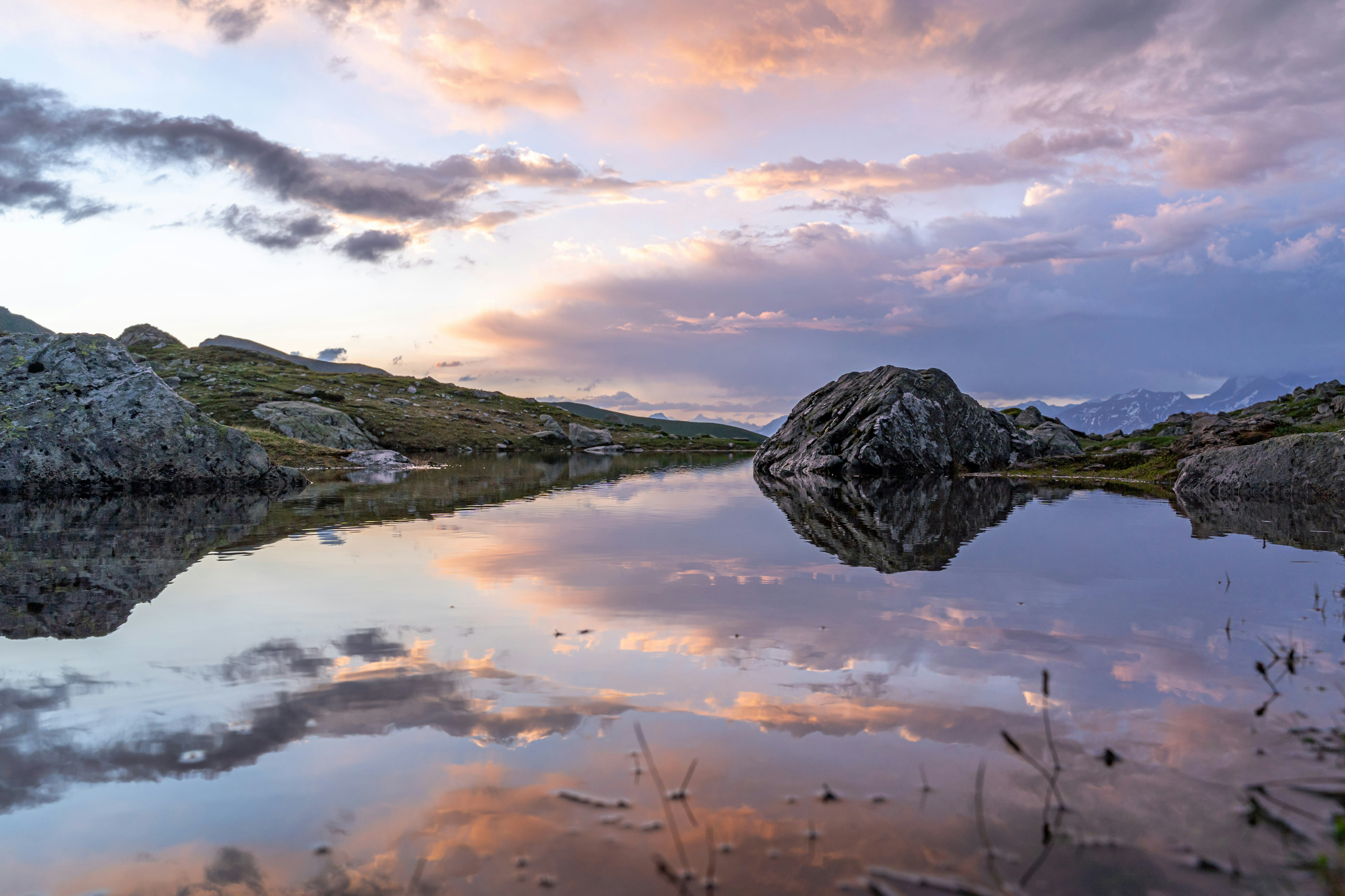 Photo de paysage de montagnes près d’un plan d’eau sous un ciel nuageux pendant la journée