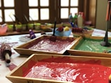 assorted paints in brown wooden trays on table