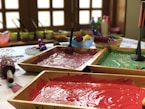 assorted paints in brown wooden trays on table