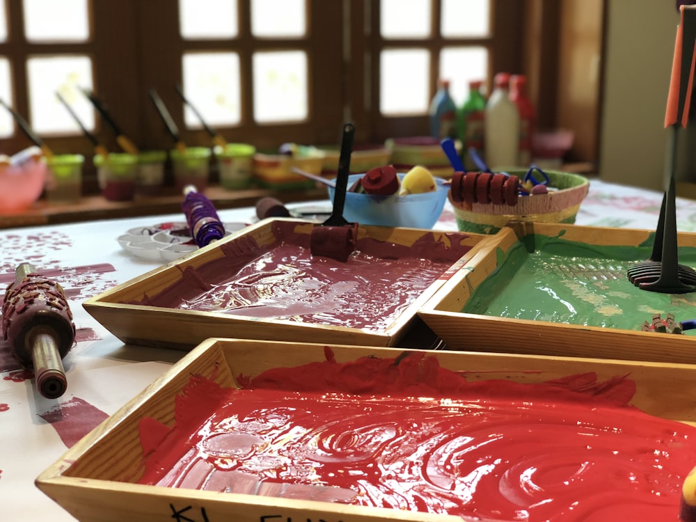 assorted paints in brown wooden trays on table